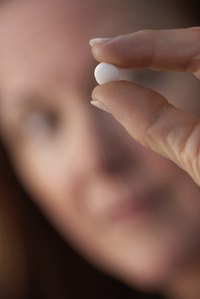 Close-up of woman holding up a supplement.