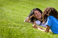 Mother and child laying on grass lawn.