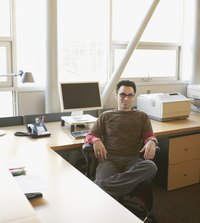 A man is sitting at his office in front of a printer.