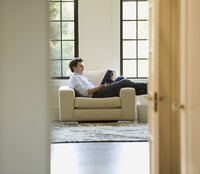A man is reading a book next to his window.