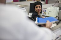 Two office workers exchanging a file folder.