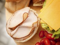 Deli meat stacked on a kaiser roll with sandwich makings.