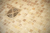 Weep holes may be surrounded by gravel beneath the drain to prevent tile installers from clogging them with mortar.