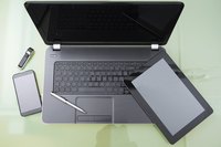 An overhead view of a laptop and portable devices on a glass desk.