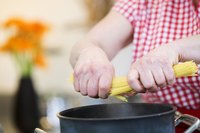 Man putting dry spaghetti in Anolon pot on stove