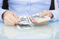 Image of a businesswoman counting dollars on her desk.