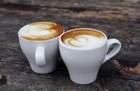 Two cappuccinos on a wooden table.