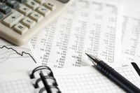 The details of a business report lie on a desk along with a calculator, pen and note journal