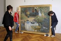Installers hanging a Monet painting in a museum.