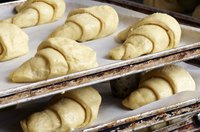 Raw phyllo dough shaped into croissants on cookie sheets