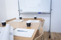 Clipboards, coffee cups and blueprints on a conference table.