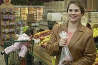 A woman holding a bag of apples in the produce section.