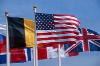 An assortment of international flags on a pole blowing in the wind.