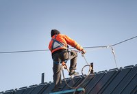 Construction worker wearing safety harness attached to wire.