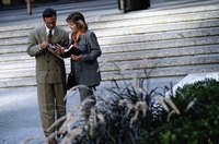 Two professionals exchanging business cards outside of a building.
