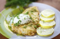 Fried fish on plate beside lemon slices