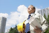 A man is on a project site holding paper plans.