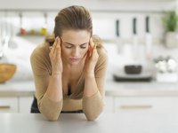 Woman with headache in kitchen