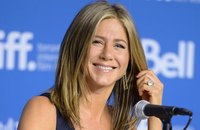 Close-up of Jennifer Aniston smiling in front of microphone.