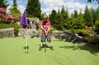 Young boy playing miniature golf