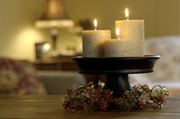 Three lit candles on a pedastal holder on a living room coffee table.