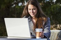 Woman with coffee and laptop and outdoor cafe.