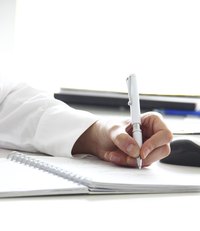 Close-up of a woman's hand writing in a steno notebook