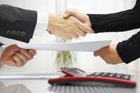 Business colleagues shake hands as they exchange a contract