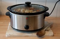 A full pot of soup slow cooking in a crock pot on the kitchen counter.