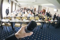 A speaker holds a microphone at a semjnar in front of a group.