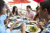 A group of friends eating on the patio of a restaurant.