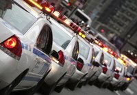 A long line of police squad cars drives down a city street