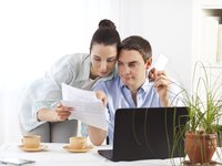 Couple reviewing invoices in front of a computer.