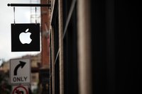 A sign with Apple Inc's logo hanging in front of a store.