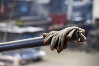 Protective gloves resting on a pipe in a factory.