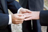Same sex couple putting on wedding bands.