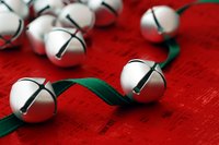 Jingle bells and green ribbon on red fabric.