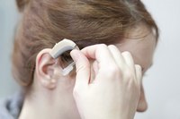 Young woman putting in hearing aid