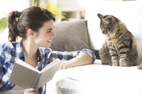 Woman looking at her cat who is sitting on the couch.