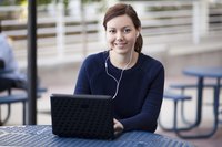 A young woman wearing headphones plugged into a laptop computer