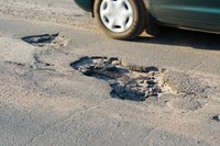 Car passing a large pothole.