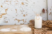 A jar of fresh buttermilk on a rustic bench next to dried whey.