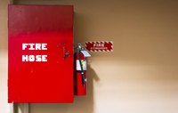 Fire extinguisher and fire hose on wall.