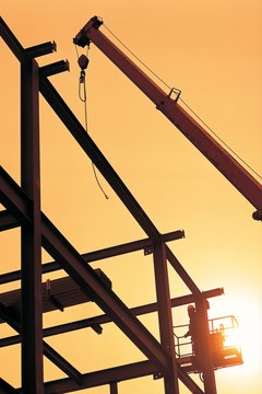 Silhouetted girders with worker and crane