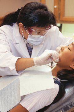 Dentist treating young woman lying in dental surgery