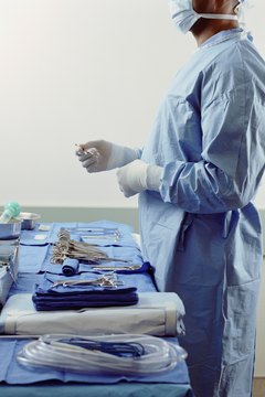 Male surgeon standing beside tray of surgical equipment, profile