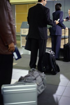 Businesspeople standing in line at airport ticketing counter, rear view
