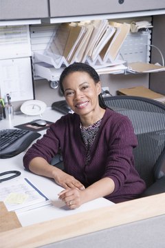 Woman sitting at desk in office, smiling, portrait
