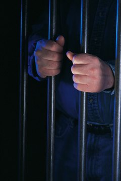 Hands holding jail cell bars