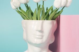 Concrete head sculpture with tulip flowers on a pastel blue background.